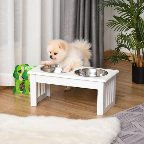 Small dog on a raised pet feeding station with two bowls in a home setting.