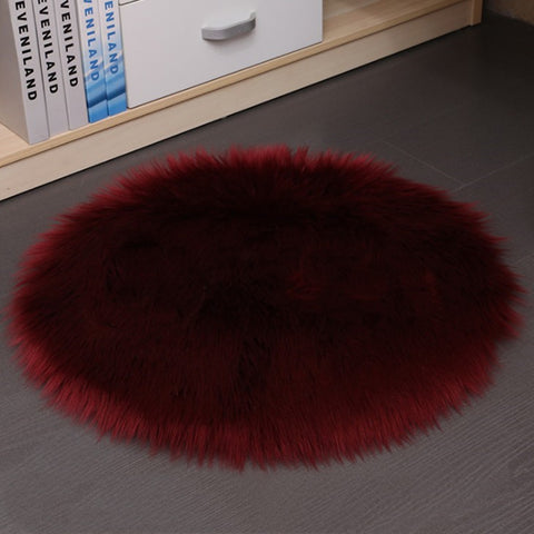Round red fur rug on a gray floor with books in the background