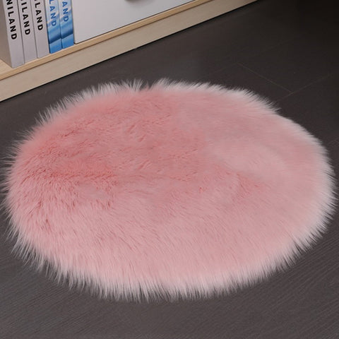 Pink fluffy rug on a dark floor with books in the background