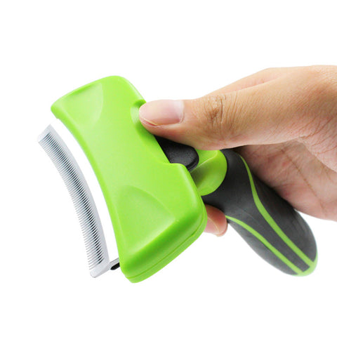 Green and black pet grooming tool held by a hand on a white background