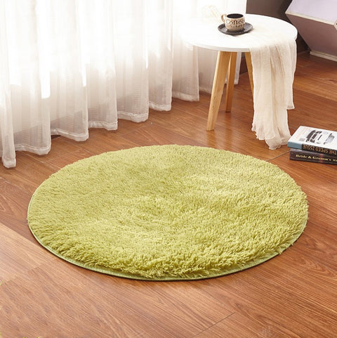 Round green rug on a wooden floor with a small table and books in the background.