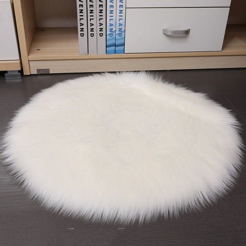 Round white fur rug on a dark floor with a bookshelf in the background.