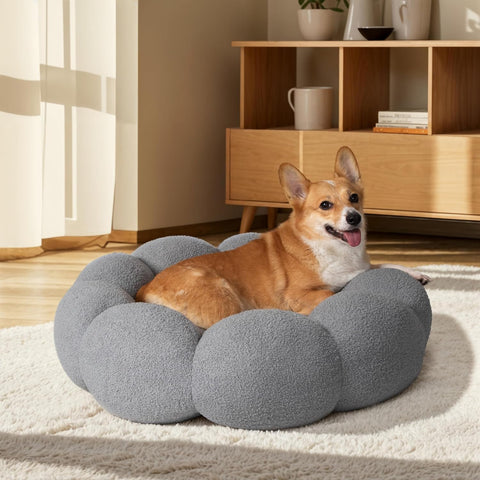 Dog lying on a gray cushioned pet bed in a room with wooden furniture and decor.