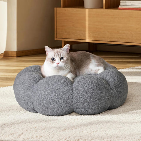 Cat lying on a gray round pet bed in a room with wooden furniture.