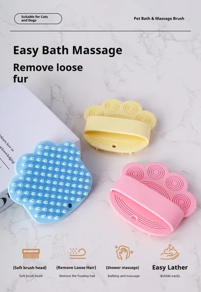 Blue, yellow and pink paw-shaped silicone pet bath brushes laid out on a light surface